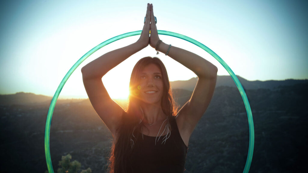 image of Woman in meditative position in front of sun approaching flow state