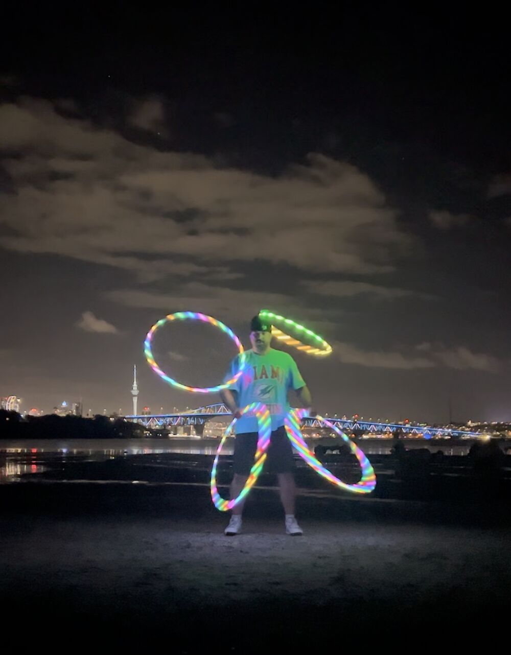 The Catching Machine spinning LED hoops at night in front of the Auckland skyline